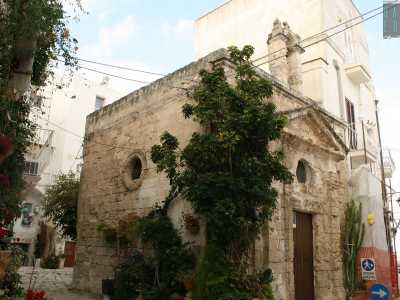 ...e piante rampicanti, che ricoprono quasi completamente una minuscola e antica cappella in tufo dalla forma quadrata dedicata ai santi Vito, Modesto e Crescenzia, con il portone d�ingresso timpanato sovrastato da un piccolo campanile a vela